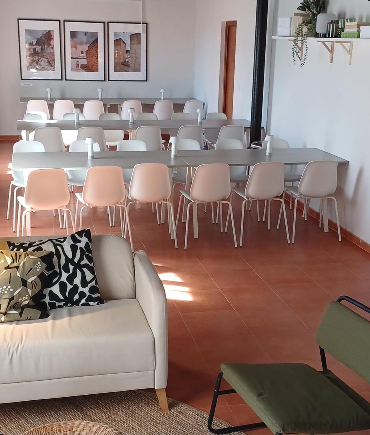 Sala de reuniones con mesas y sillas blancas.