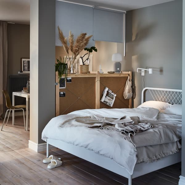 Sala onde uma combinação de armários que divide o espaço e estores de correr fixados no teto formam um recanto com uma cama de casal.