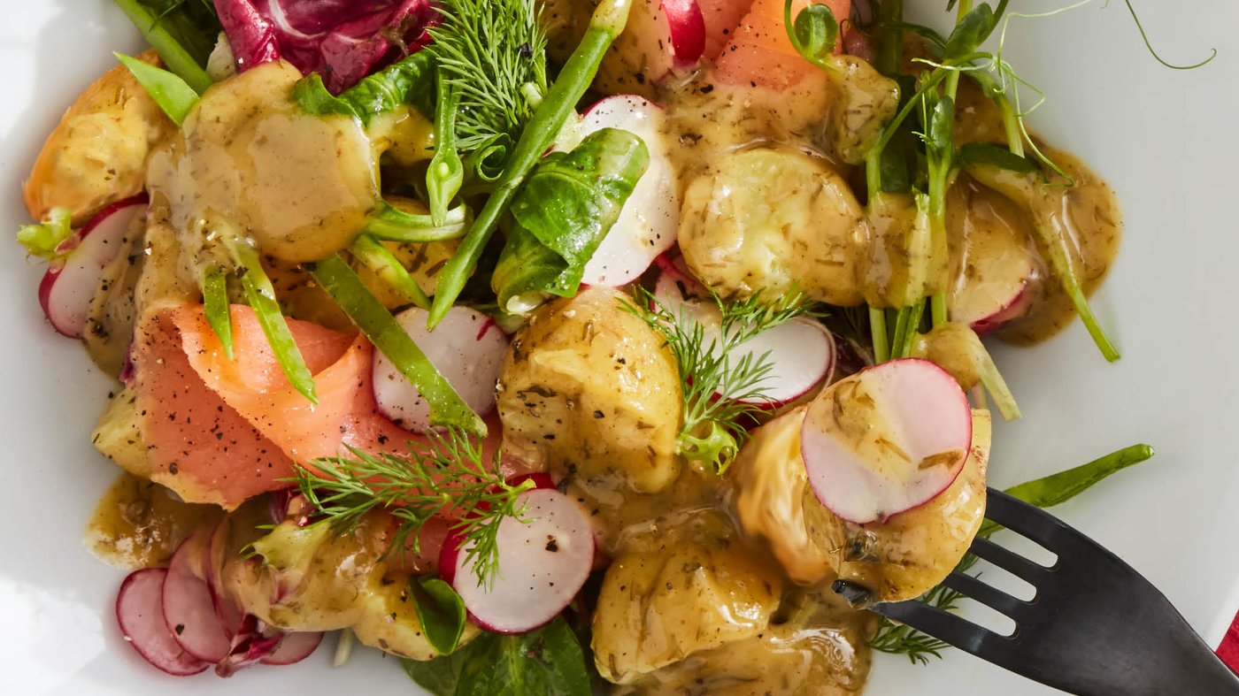 Šalát z údeného lososa SJÖRAPPORT so zemiakmi, listovým šalátom, kôprom a omáčkou na lososa SÅS SENAP & DILL na bielom tanieri s čiernou vidličkou TILLAGD.