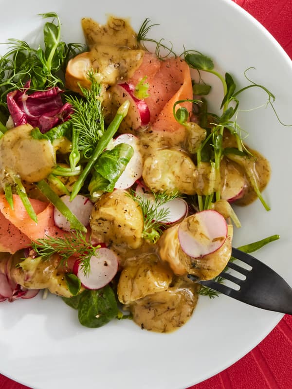 Šalát z údeného lososa SJÖRAPPORT so zemiakmi, s listovým šalátom, kôprom a omáčkou na lososa SÅS SENAP & DILL na bielom tanieri s čiernou vidličkou TILLAGD.