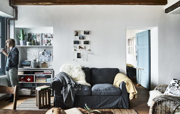Salon avec murs blancs et canapé gris.
