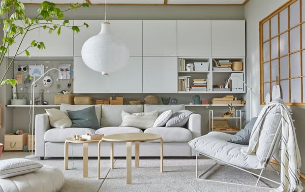 Salon lumineux avec fauteuil HAVSTEN, nombreuses armoires murales blanches et suspension ronde blanche.