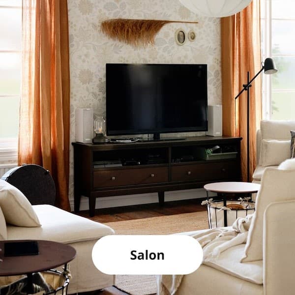 Salon où est exposé un meuble télé, des fauteuils et des rideaux orange