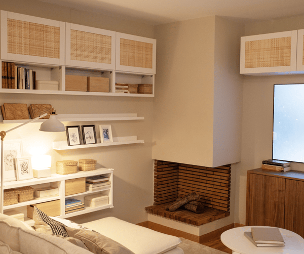 Salón reformado con chimenea, estanterías, cajas, mesa y sofá.