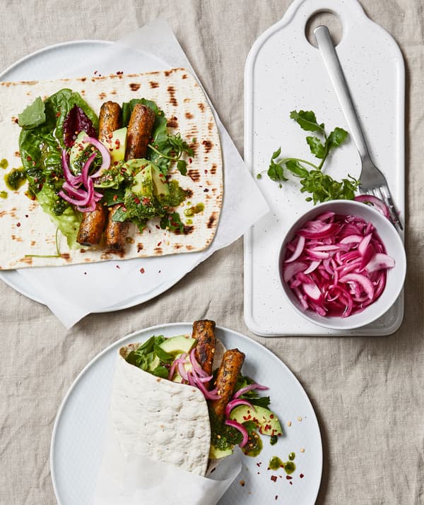 Salsitxes i amanida sobre plats blancs.