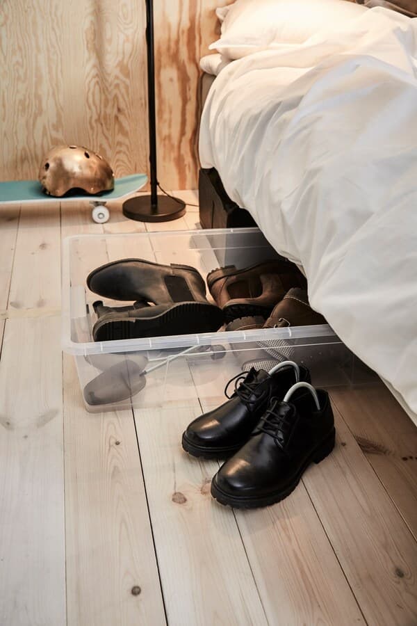 SAMLA box with lid with winter boots in it, half pushed under a bed