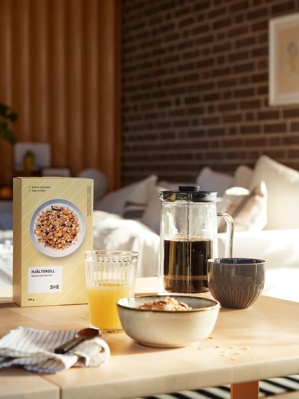 Sarapan yang lazat disediakan di atas meja ruang tamu, termasuk segelas jus, serahi berisi kopi dan muesli HJÄLTEROLL.