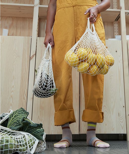 Sárga pulóveres lány, gyümölcsökkel és zöldségekkel.