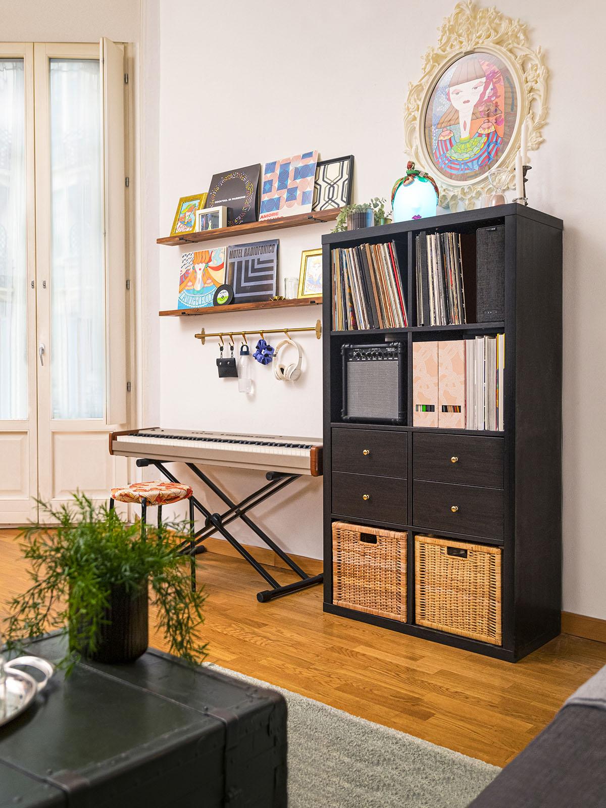 Scaffale KALLAX con dischi all'interno in un soggiorno accogliente con parquet, mensole e una tastiera appoggiata al muro. 