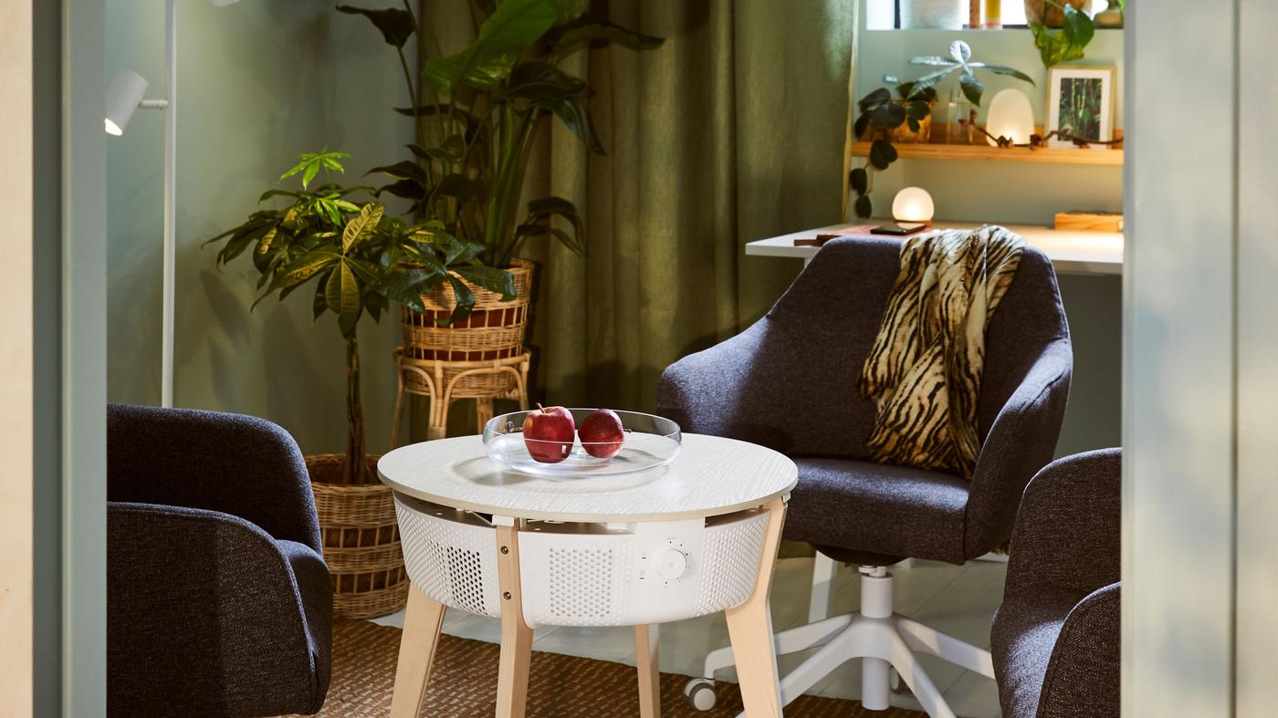 Scaune de conferință TOSSBERG în jurul unei mese STARKVIND cu purificator de aer într-o cameră cu draperii și multe plante.