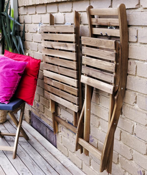 Scaune pliabile din lemn suspendate pe un perete de cărămidă.