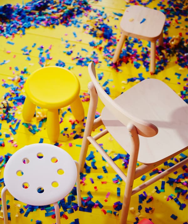 Scaunele din plastic MAMMUT și MARIUS și scaunul RÖNNINGE din lemn masiv de mesteacăn așezate pe podea, în timpul unei petreceri. 