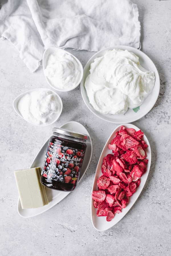 Schalen mit Joghurt oder Sahne, Marmelade, Butter und geschnittenen Erdbeeren auf heller Oberfläche.