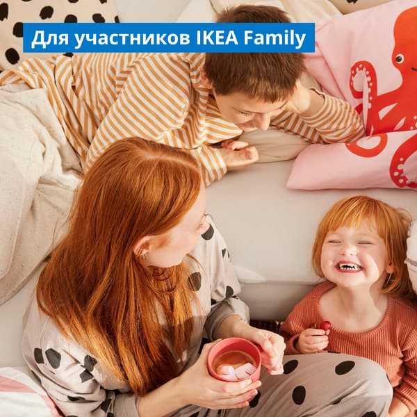 Счастливая семья собралась в гостиной у углового дивана: рыжеволосая мама с кружкой какао смотрит, как смеётся её маленькая дочь, а старший брат лежит на диване рядом.