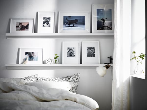 Schilderijenplanken boven bed met fotolijsten erop