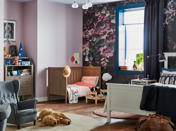 Schlafzimmer mit lila geblümter Tapete an einer Wand, in dem Eltern & Baby zusammen schlafen können