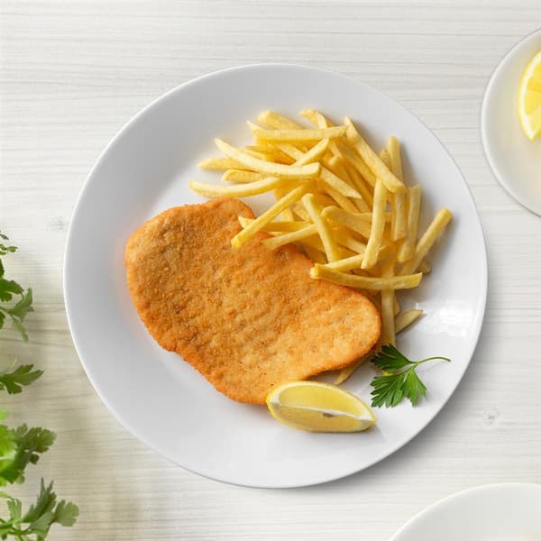 Schnitzel mit Pommes auf einem Teller mit Zitrone präsentiert.