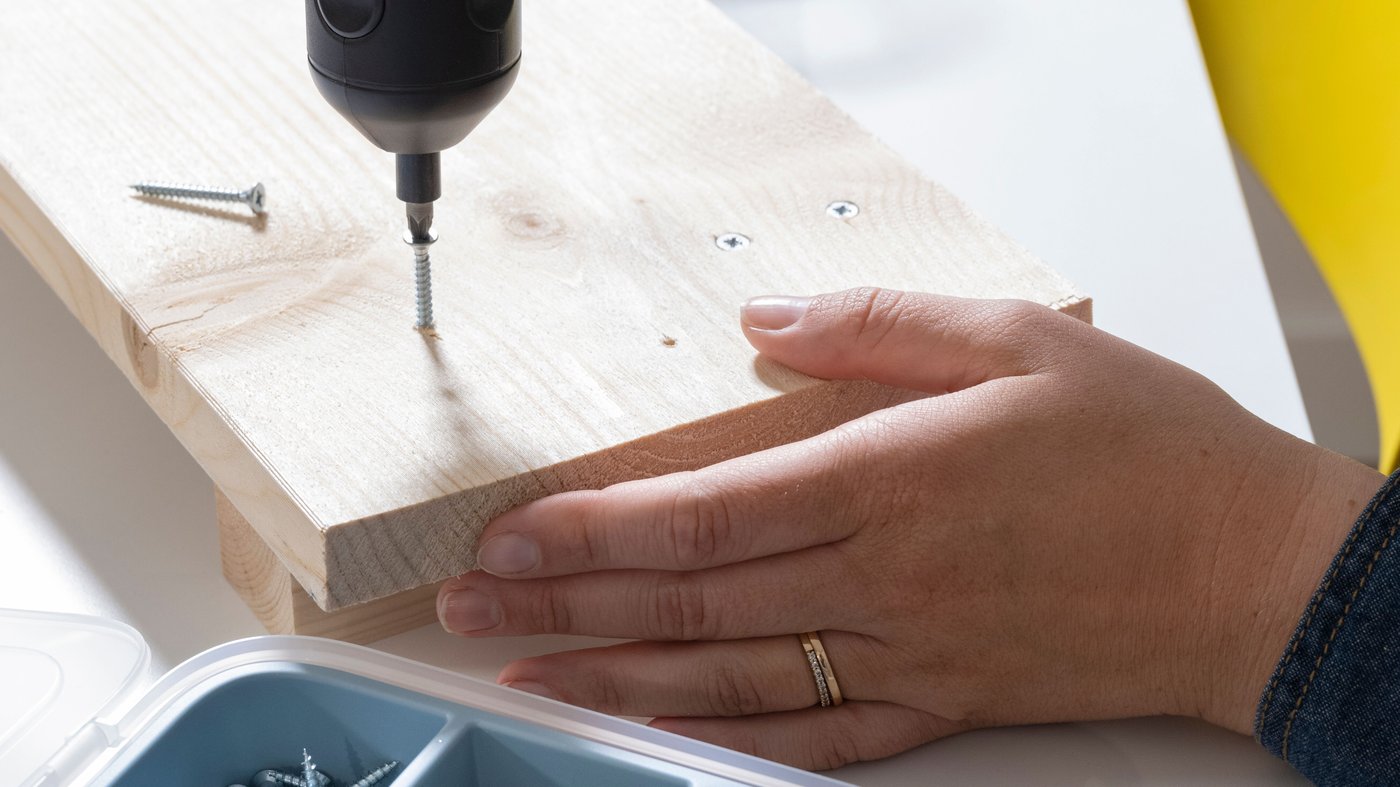 Schroeven worden in een stuk hout gedraaid met behulp van een elektrische schroevendraaier.