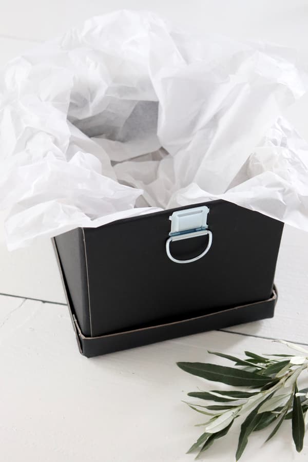 Schwarze Box wird mt weißem Seidenpapier ausgekleidet.