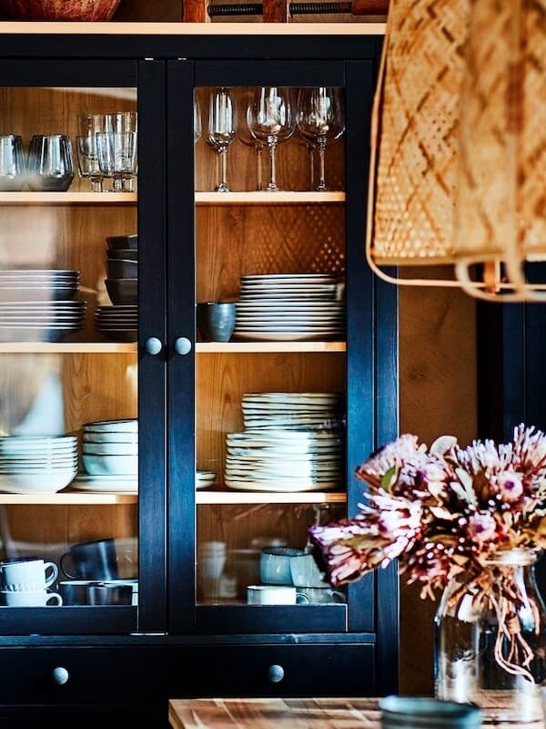 Schwarze Vitrinenschränke mit Gläsern und gestapeltem Geschirr.