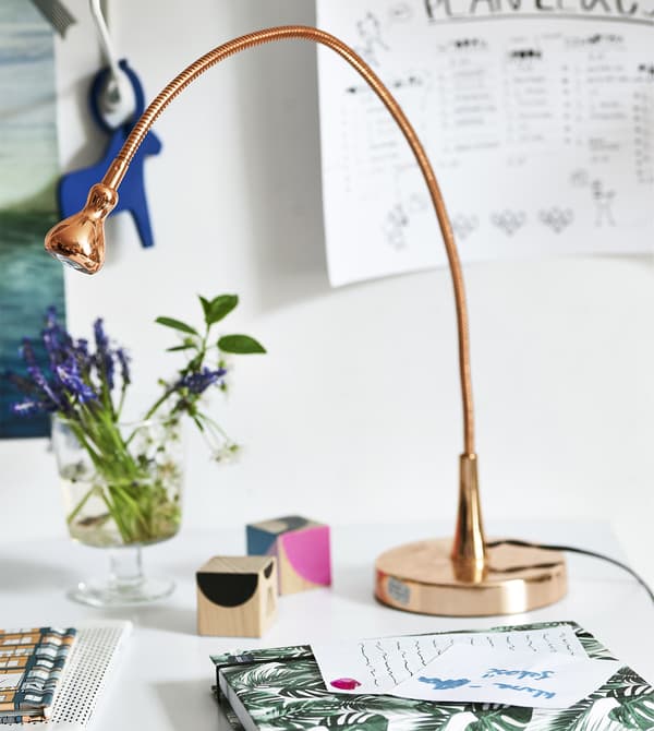 Scrivania arredata con una lampada di rame, fiori e oggetti –IKEA