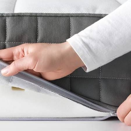 Se ven las manos de una persona sacando la funda del colchón.