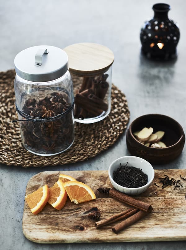 Seasonal spices in jars and cinnamon sticks on a board.