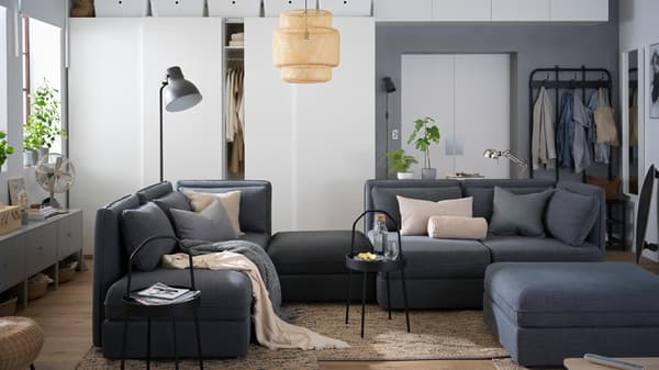 Seating and storage in a one-room city apartment, including a large VALLENTUNA modular sofa and PAX wardrobes.