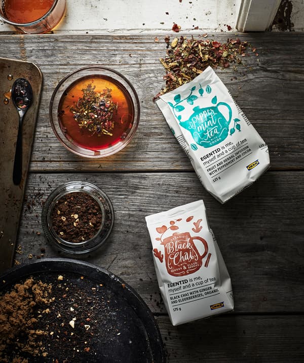 Sección de mesado ou mesa de madeira xunto a unha fiestra. Paquetiños abertos de té xunto a un expositor de preparación de infusións.