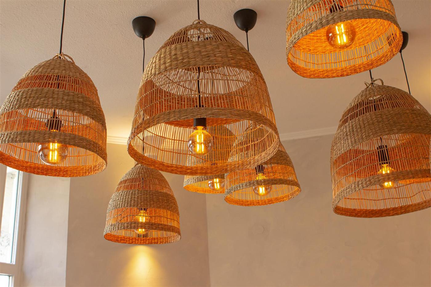 Sechs Naturfaser Hängeleuchten hängen an der Decke.