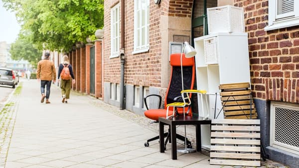 Second-life IKEA furniture stands neatly on the sidewalk in front of a brick building, ready for sustainable reuse.