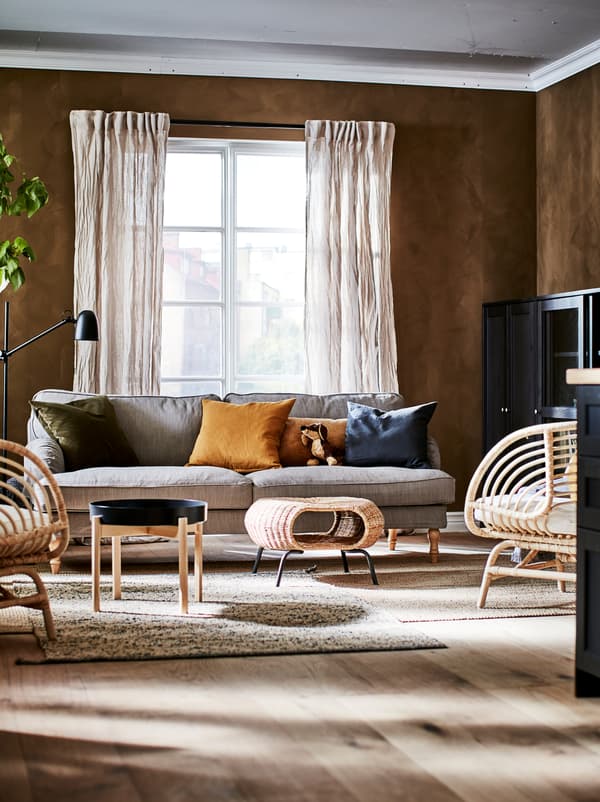 Section d’un salon peint et meublé dans des tons naturels et riches où l’on trouve du rangement, des places assises, une table basse et un repose-pieds GAMLEHULT.
