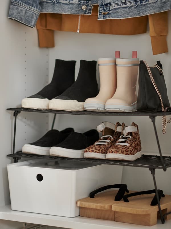 Section d’une armoire-penderie dans laquelle une étagère à chaussures GREJIG siège au milieu d’autres vêtements et accessoires.