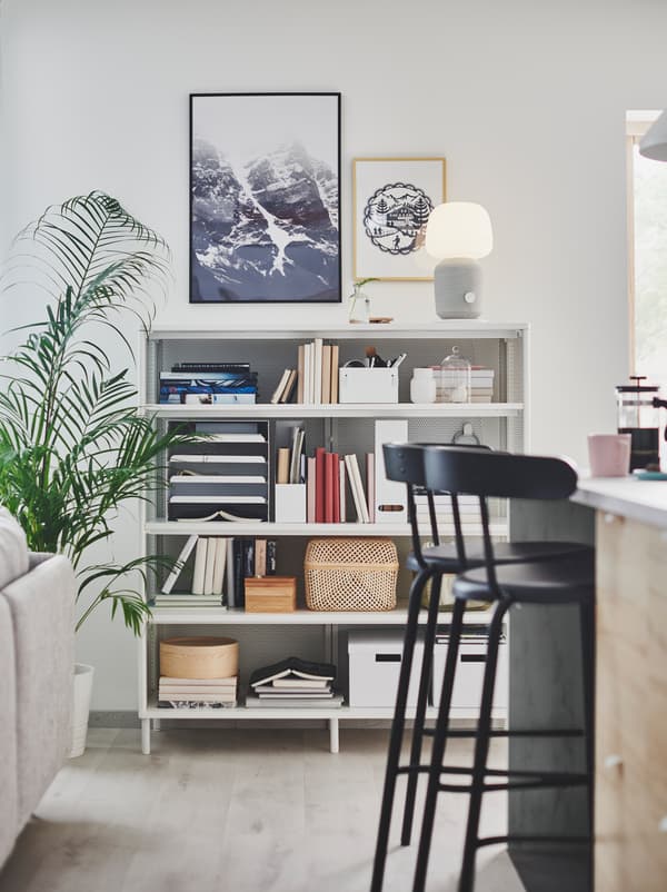 Section d’une pièce à aire ouverte où l’on peut voir un îlot de cuisine, un canapé de salon et une étagère BEKANT.