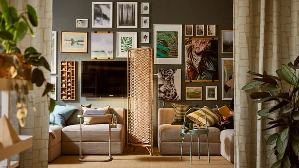 Sections of a JÄTTEBO sofa on either side of a TOLKNING rattan room divider, all beneath a wall full of framed art.