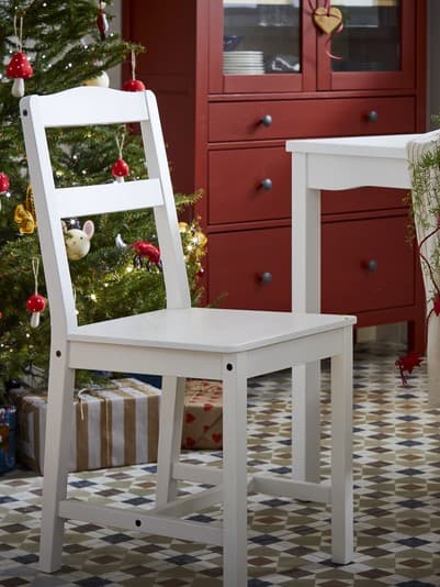 Sedia e tavolo bianchi. Dietro, un albero di Natale decorato e un mobile rosso HEMNES con vetrina.
