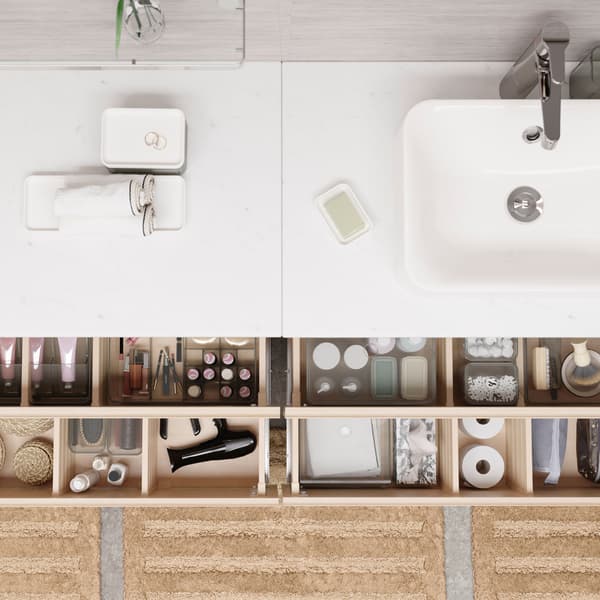 Seen from above are four open bathroom drawers where things are nicely organised in see-through boxes with compartments.