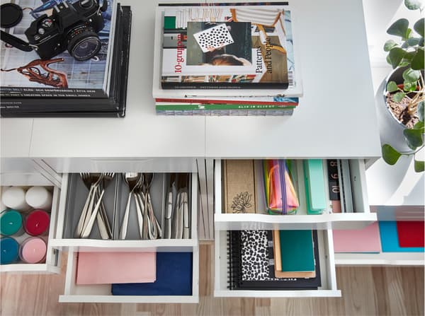 Seen from above is a white drawer unit with books on the top surface, and drawers are open to show storage inside.