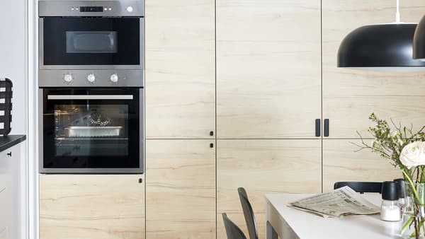 Seinään asennettavat IKEA METOD -kaapistot, joissa on ASKERSUND-ovet vaaleasta saarnipuusta, sisäänrakennettu uuni ja mikroaaltouuni.