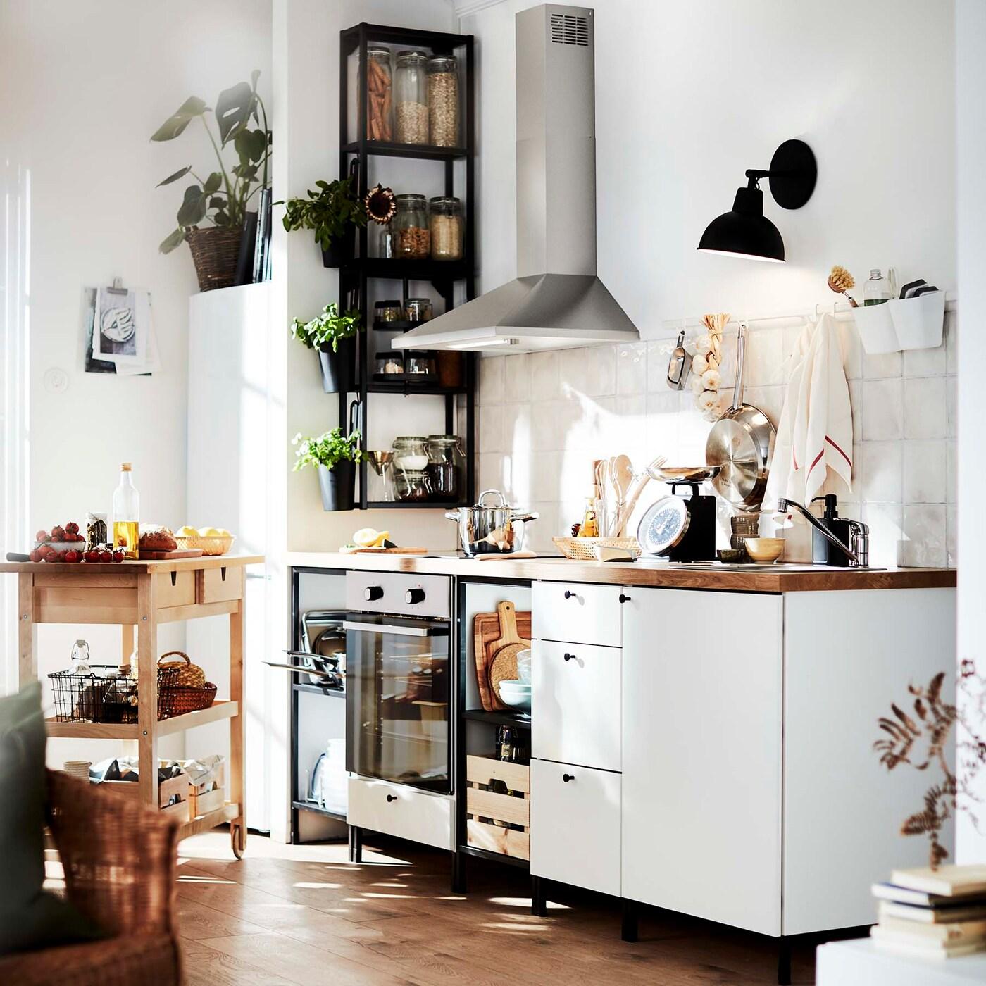 Seinään kiinnitettävät RYTMISK-liesituuletin ja SKURUP-valaisin säästävät tilaa vaaleassa ENHET keittiössä.