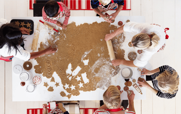 Seis personas alrededor de una mesa rectangular. Unas amasan otras cortan galletas de navidad con implementos de repostería de IKEA.