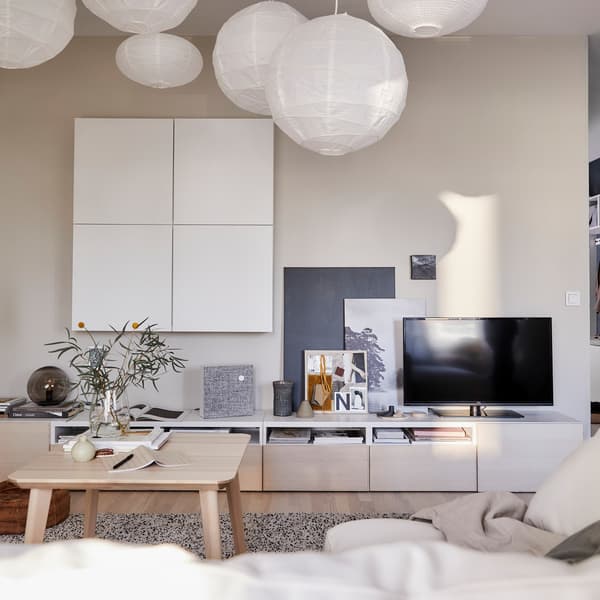 Séjour avec des armoires blanches au mur et un meuble télé IKEA BESTÅ.