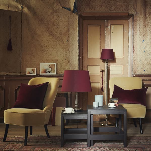 Séjour avec fauteuils jaunes, coussins en velours et tables gigognes HAVSTA brunes.