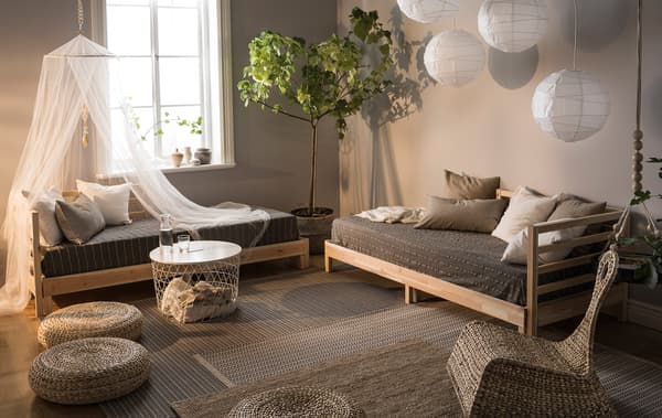 Séjour dans des couleurs naturelles, décoré avec des divans, des lampes en papier, des coussins en tissu et des plantes vertes.