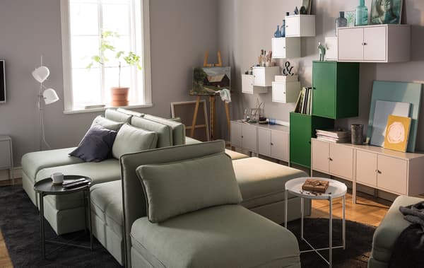 Séjour décoré avec des canapés modulaires et beaucoup de rangements muraux.