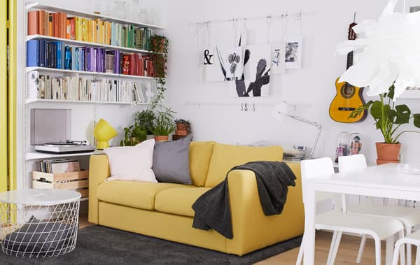 Séjour décoré en blanc et jaune, avec des touches d’accent, des œuvres d’art au mur et une table de salle à manger.
