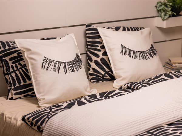 Selbstbestickte Polster in einem Bett mit Schwarz-weißer Bettwäsche.