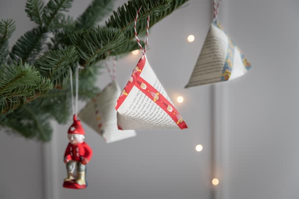 Selbstgemachte Geschenktäschchen in Form von Dreieckstüten hängen an einem Baum.