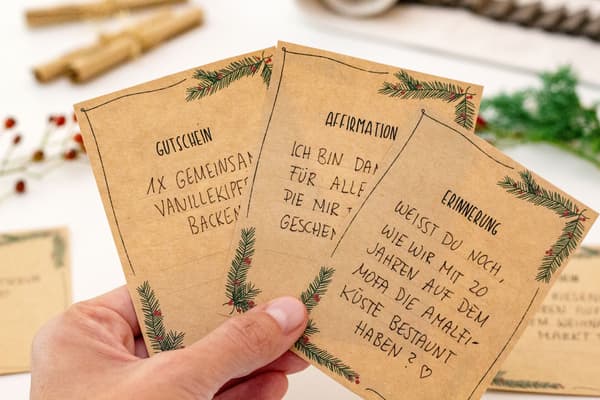 Selbstgeschriebene Gutscheine und Grüße auf braunem Kraftpapier mit gemalter Verzierung. 
