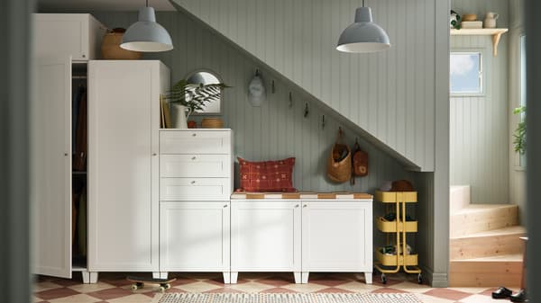 Série d’armoires et de penderies PLATSA blanches placées stratégiquement sous un escalier.